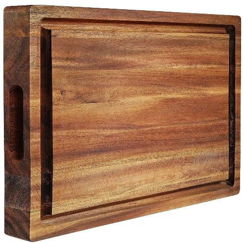 Angled perspective view of thick acacia wood butcher block showing deep carved juice grooves and inset side handle