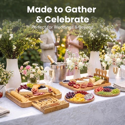 NovoBam bamboo charcuterie cheese board sets and round fruit platters styled on a luxury outdoor wedding celebration banquet table with wine, cheeses, crackers, and fruits