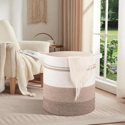 Extra large 120L round woven cotton rope laundry hamper in cozy bedroom by armchair with throw blanket