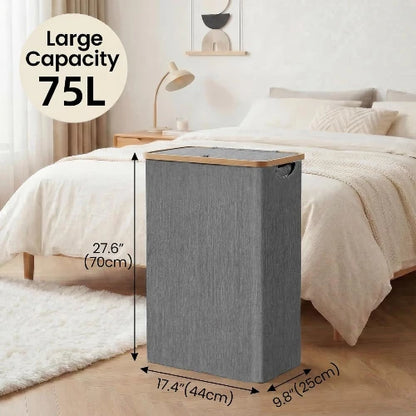 75L slim gray laundry hamper with lid and bamboo handles placed beside a bed showing dimensions of 17.4 inch length, 9.8 inch width, and 27.6 inch height