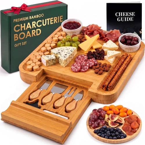 NovoBam square bamboo charcuterie board loaded with appetizers and meats, featuring open cutlery drawer, round fruit platter, and green gift box.