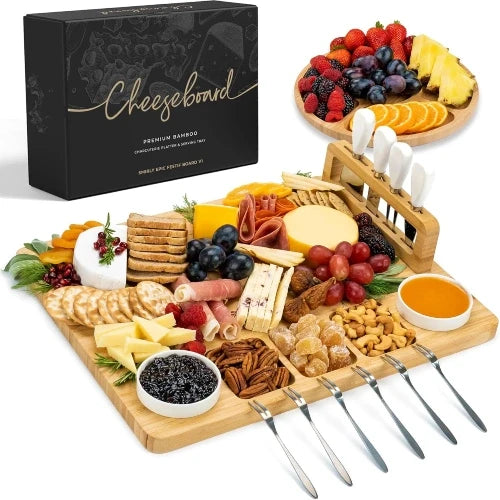 Complete NovoBam 17x13 bamboo charcuterie board set with premium gift box, separate round fruit platter, upright magnetic cheese knife stand, ceramic dip bowls, and tasting forks fully arranged with appetizers