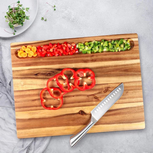Top-down view of acacia wood cutting board showing carved prep sorting compartment holding diced vegetables with chef knife