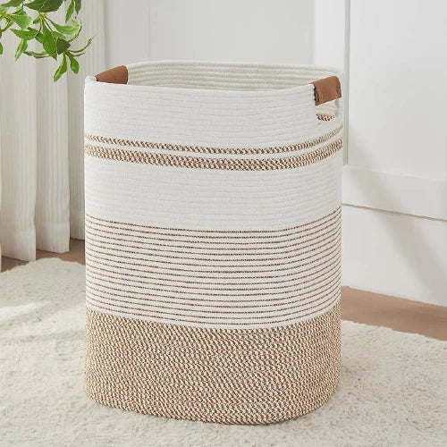 Tall rectangular woven cotton rope laundry hamper in brown and white stripes with leather handles, standing upright on a rug.