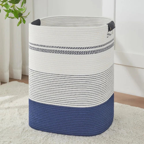 Tall rectangular woven cotton rope laundry hamper in dark blue and white stripes with durable handles, standing upright in a bedroom.