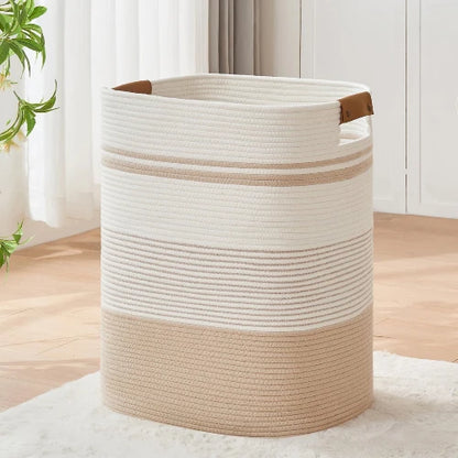 Tall rectangular woven cotton rope laundry hamper in off-white and tan with leather handles, standing upright in a modern home.